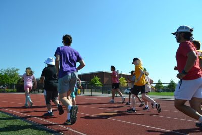 A photo of athletes and coaches running on a track. 
