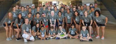Camp Abilities Texas group photo. Athletes, coaches, and staff are wearing light gray shirts and smiling for group photo.