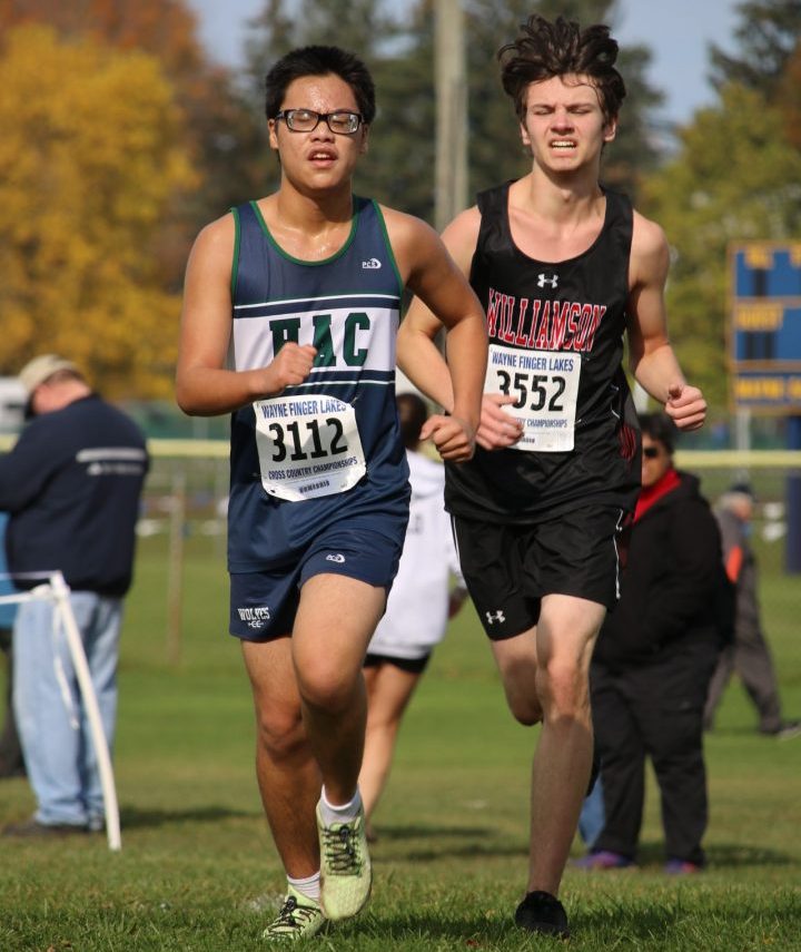 Chris in the middle of a run. His opponent is behind him in the background. Chris is wearing his team's jersey that is blue and white with the initials HAC across the front.