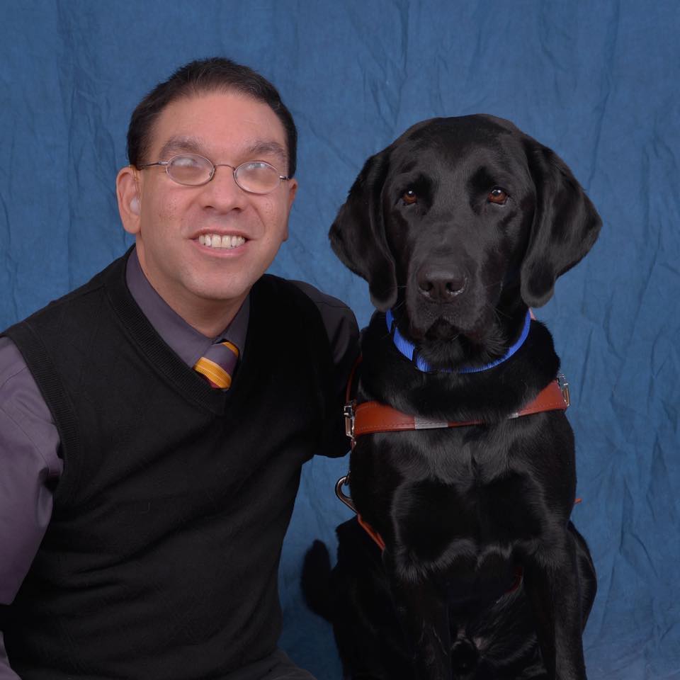 Eddie smiling for a photo with his service dog beside him.