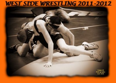Paul wresting with an opponent. He is holding his opponent on the ground. Both are wearing wresting shoes and head gear. At the top of the photo it says West Side Wrestling 2011-2012. 