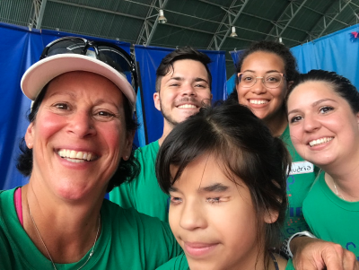 Lauren and 4 other people smiling for a selfie. Everyone is wearing their green camp brazil tshirts. 